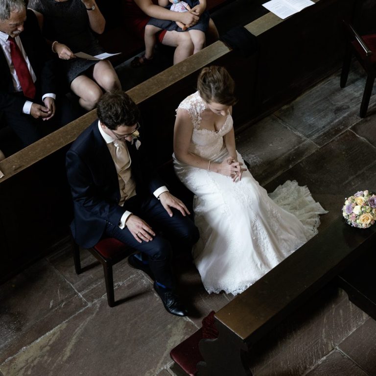 Brautpaar sitzt in der Kirche und hört andächtig der Predigt zu.